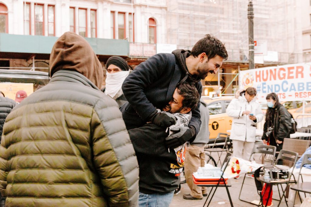 Wie Zohran Mamdani Politik neu brandet und was Kommunikationsprofis daraus lernen können Zohran Mamdani umarmt einen Unterstützer während einer Kundgebung der New York Taxi Workers Alliance in Manhattan.