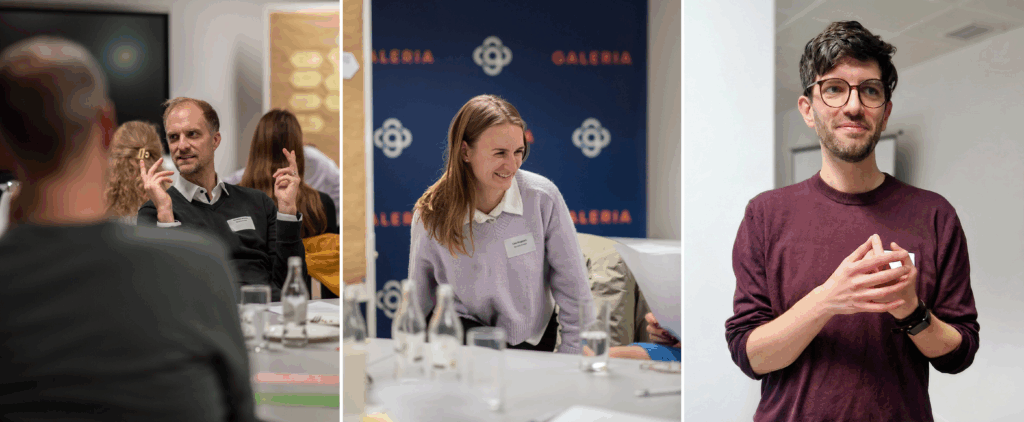 Drei Personen in einem Workshopraum während einer Diskussion und Gruppenarbeit. Links ein Mann im Gespräch, in der Mitte eine Frau, die lächelnd an einem Tisch sitzt, rechts ein Mann, der vor der Gruppe spricht.